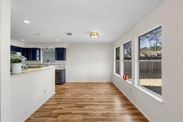 kitchen featuring blue cabinets, dishwasher, and light hardwood / wood-style floors