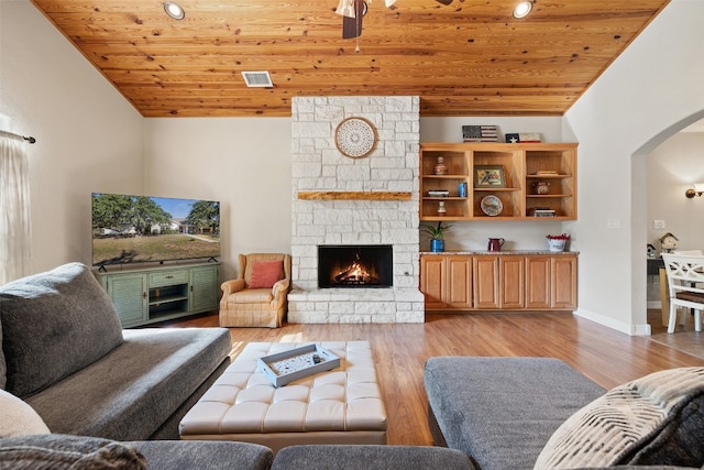 living room featuring a stone fireplace, light hardwood / wood-style flooring, wooden ceiling, and vaulted ceiling