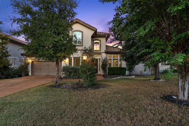 mediterranean / spanish-style home with a yard and a garage