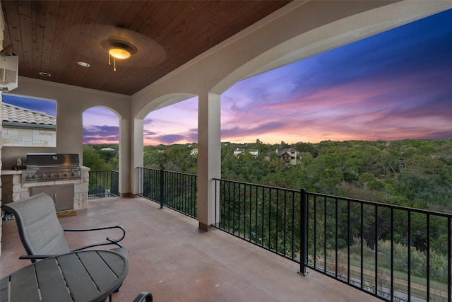 balcony at dusk with an outdoor kitchen, area for grilling, and a patio