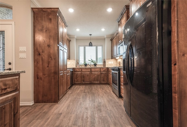 kitchen with stainless steel appliances, tasteful backsplash, pendant lighting, hardwood / wood-style flooring, and ornamental molding