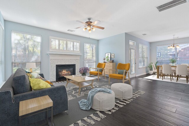 living room with ceiling fan with notable chandelier and dark hardwood / wood-style floors