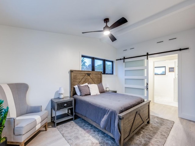 bedroom with a barn door, ceiling fan, light hardwood / wood-style flooring, and lofted ceiling