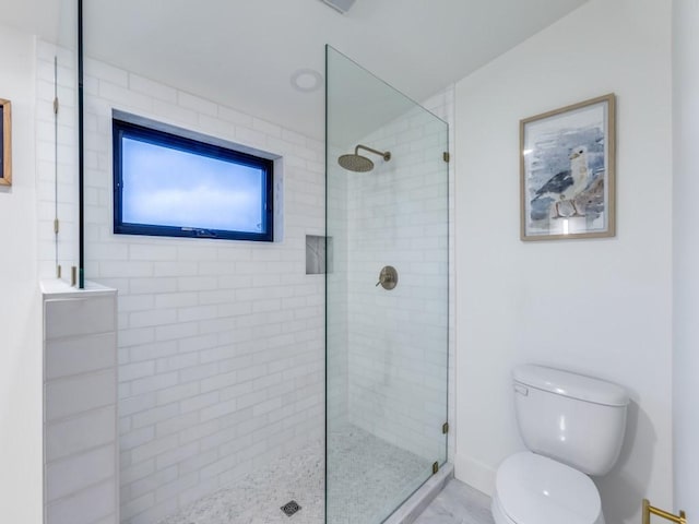 bathroom featuring tiled shower and toilet