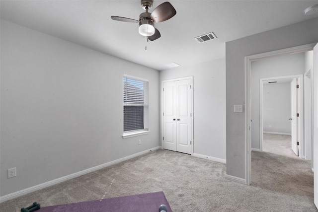 unfurnished bedroom featuring ceiling fan, light colored carpet, and a closet