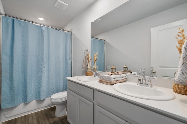 full bathroom featuring toilet, hardwood / wood-style floors, vanity, and shower / tub combo with curtain