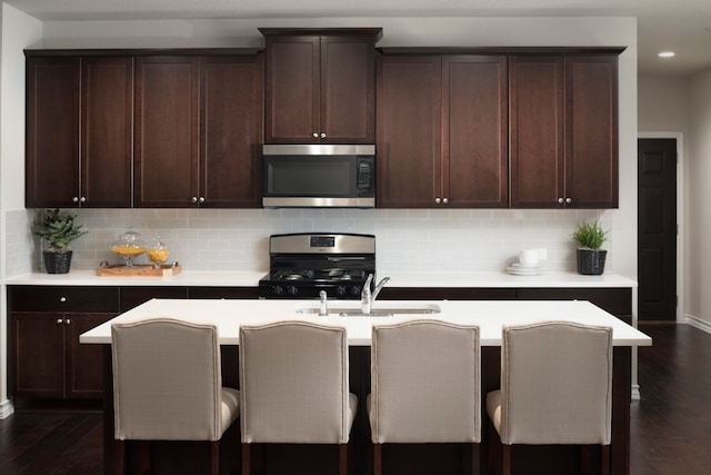 kitchen featuring a breakfast bar area, sink, stainless steel appliances, and dark hardwood / wood-style floors