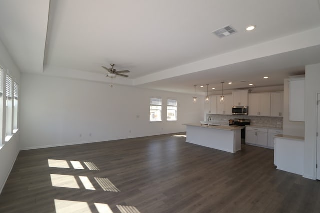 kitchen with hanging light fixtures, stainless steel appliances, dark hardwood / wood-style floors, a center island with sink, and white cabinets