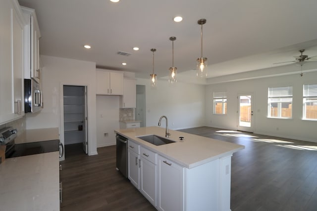 kitchen featuring dark hardwood / wood-style flooring, sink, white cabinetry, hanging light fixtures, and an island with sink