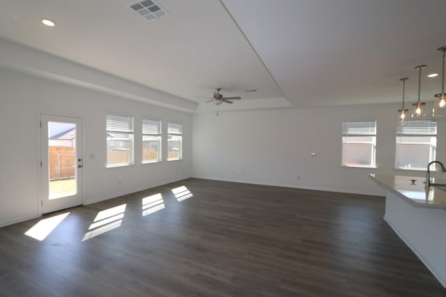 unfurnished living room featuring a wealth of natural light, dark hardwood / wood-style flooring, ceiling fan, and sink