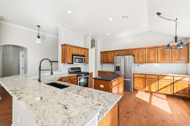 kitchen with decorative light fixtures, a center island, decorative backsplash, and stainless steel appliances