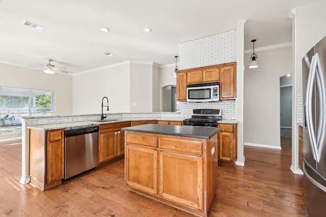 kitchen with pendant lighting, a center island, sink, and appliances with stainless steel finishes