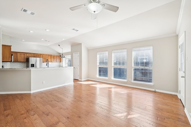 unfurnished living room with crown molding, ceiling fan, light hardwood / wood-style floors, and vaulted ceiling