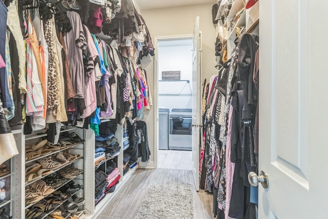 spacious closet with washer and clothes dryer and light hardwood / wood-style floors