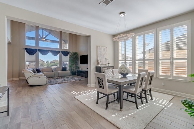 dining area with plenty of natural light, light wood-type flooring, and an inviting chandelier