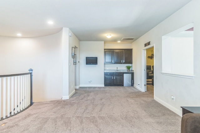 kitchen with dark brown cabinetry, stainless steel fridge, sink, and light colored carpet