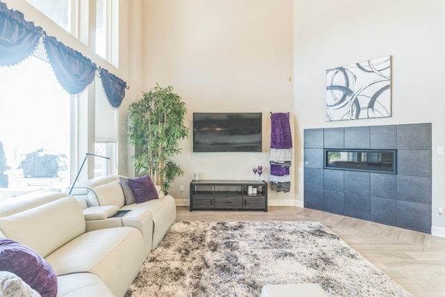 living room featuring parquet flooring, a healthy amount of sunlight, and a tiled fireplace