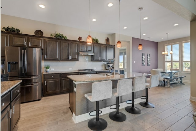 kitchen with sink, light stone counters, pendant lighting, a center island with sink, and appliances with stainless steel finishes