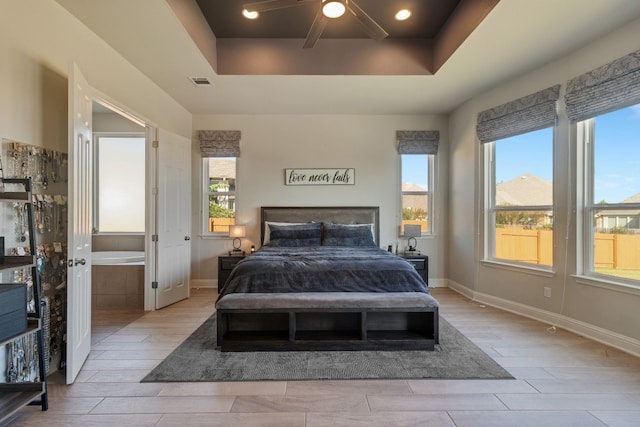 bedroom featuring ceiling fan, a tray ceiling, and multiple windows