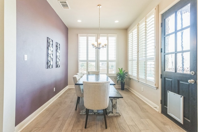 dining room with a healthy amount of sunlight, light wood-type flooring, and an inviting chandelier