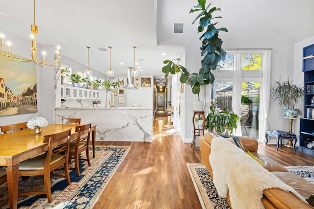 dining area with light hardwood / wood-style flooring, a high ceiling, and an inviting chandelier