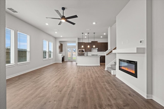 unfurnished living room with ceiling fan and light hardwood / wood-style flooring