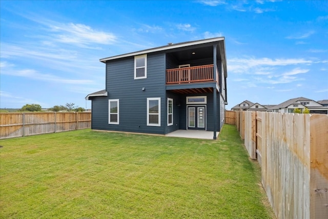 rear view of property with a patio area, a balcony, and a yard