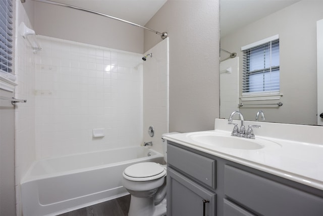 full bathroom with hardwood / wood-style floors, vanity, tiled shower / bath combo, and toilet