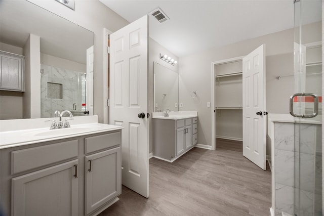 bathroom with hardwood / wood-style floors, vanity, and a shower with door