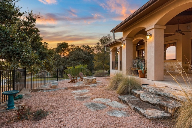 yard at dusk with a patio area, ceiling fan, and an outdoor fire pit