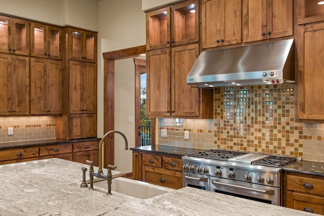 kitchen featuring range with two ovens, light stone countertops, sink, and tasteful backsplash