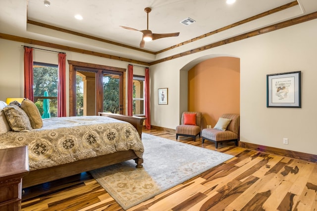 bedroom with a raised ceiling, ceiling fan, light hardwood / wood-style flooring, and crown molding