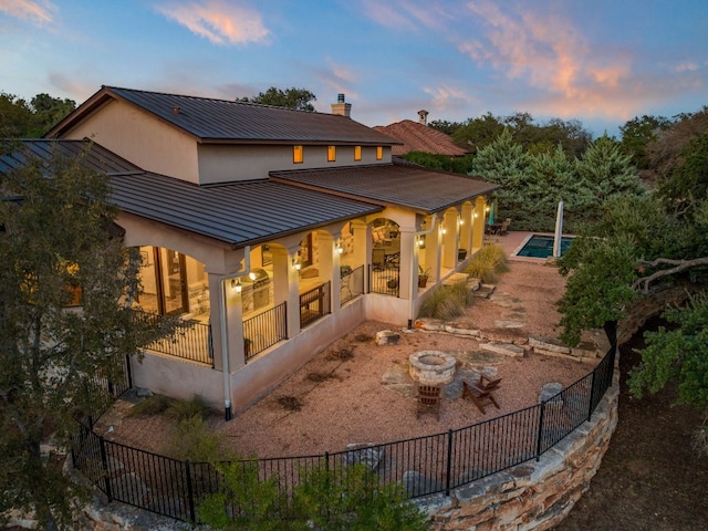 back house at dusk featuring a fenced in pool, an outdoor fire pit, and a patio area