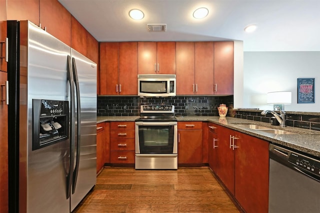 kitchen featuring backsplash, stainless steel appliances, dark wood-type flooring, sink, and stone countertops