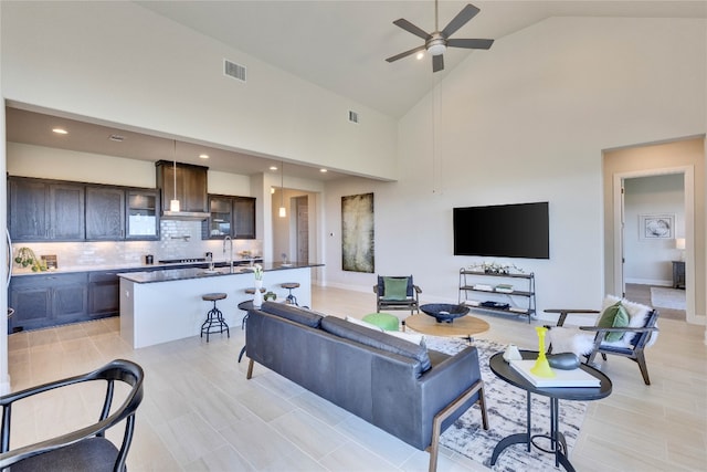 living room featuring ceiling fan, sink, and high vaulted ceiling