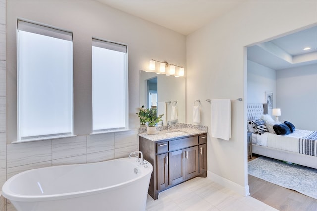 bathroom with hardwood / wood-style flooring, vanity, tile walls, and a tub