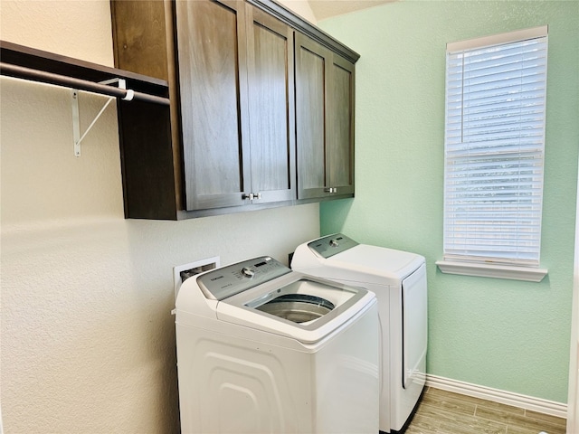 laundry room featuring cabinets, light wood-type flooring, and washer and clothes dryer