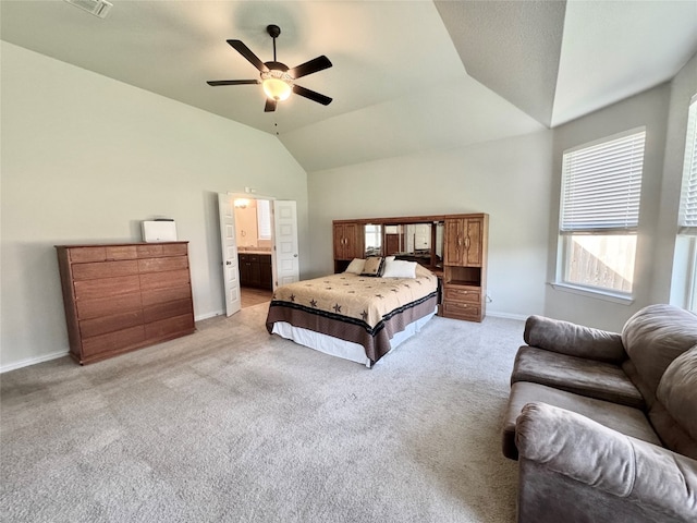 bedroom featuring light carpet, vaulted ceiling, ensuite bath, and ceiling fan