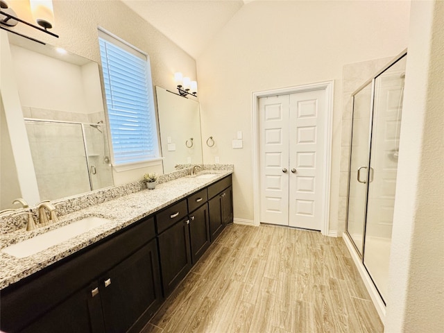 bathroom featuring vanity, wood-type flooring, lofted ceiling, and a shower with door