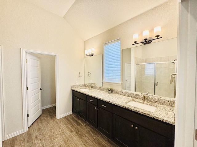 bathroom featuring vanity, lofted ceiling, a textured ceiling, walk in shower, and wood-type flooring