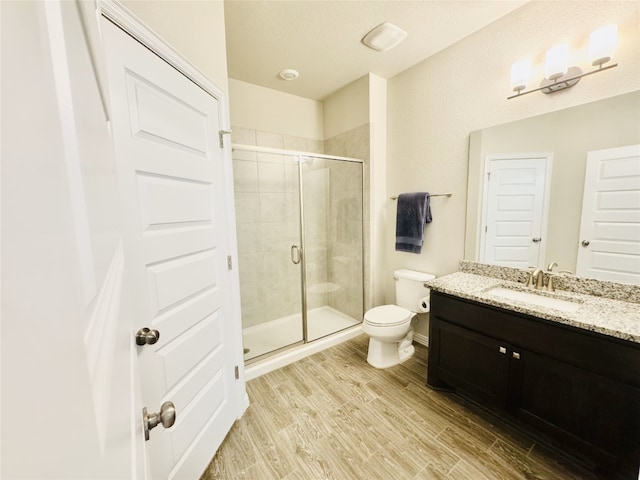 bathroom with a textured ceiling, toilet, vanity, a shower with shower door, and hardwood / wood-style flooring