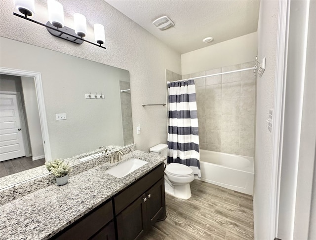 full bathroom featuring hardwood / wood-style floors, a textured ceiling, toilet, shower / tub combo with curtain, and vanity