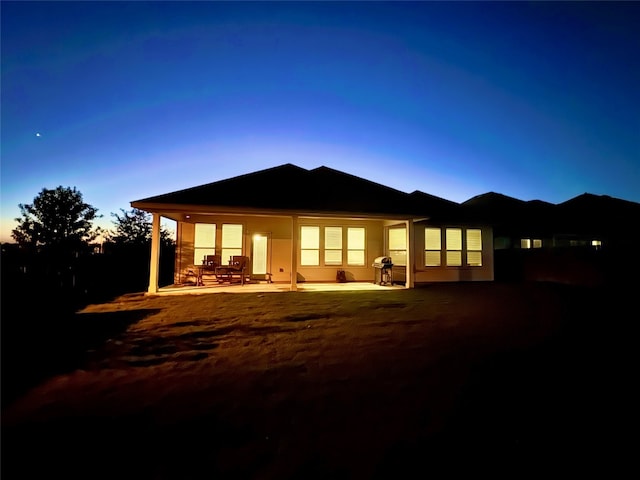 back house at dusk with a patio