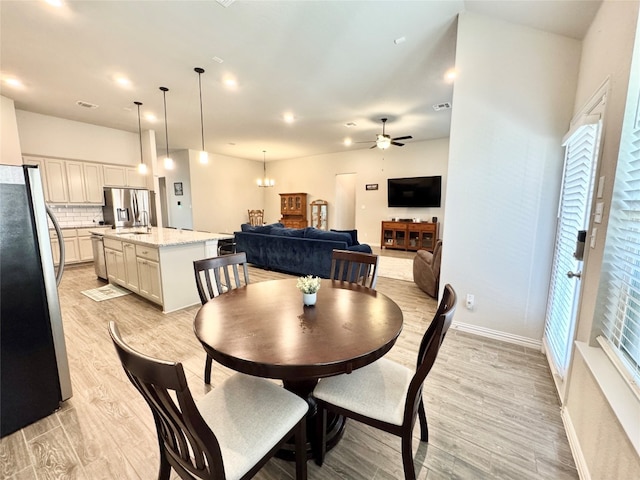 dining space featuring ceiling fan with notable chandelier and light wood-type flooring