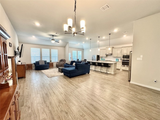 living room featuring ceiling fan with notable chandelier and light hardwood / wood-style floors