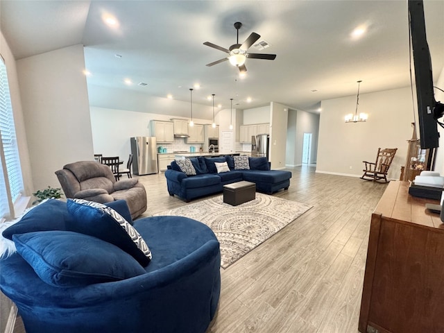 living room with ceiling fan with notable chandelier and light hardwood / wood-style flooring