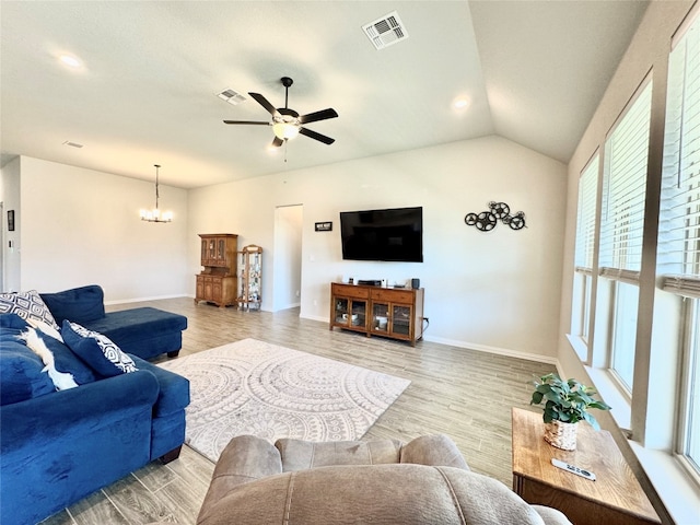 living room featuring ceiling fan with notable chandelier, vaulted ceiling, and light hardwood / wood-style flooring