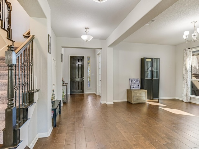 foyer with dark hardwood / wood-style flooring, a textured ceiling, and a notable chandelier