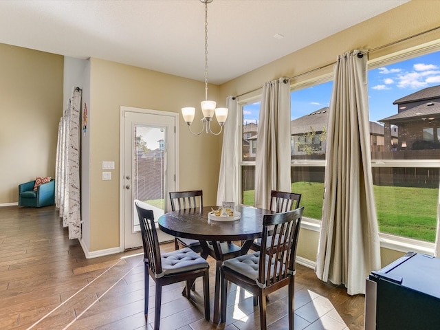 dining space featuring dark hardwood / wood-style floors, a healthy amount of sunlight, and an inviting chandelier