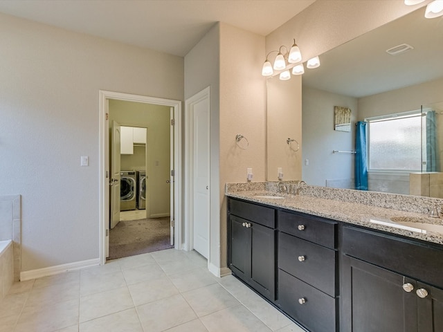 bathroom with tile patterned flooring, vanity, a bathtub, and separate washer and dryer